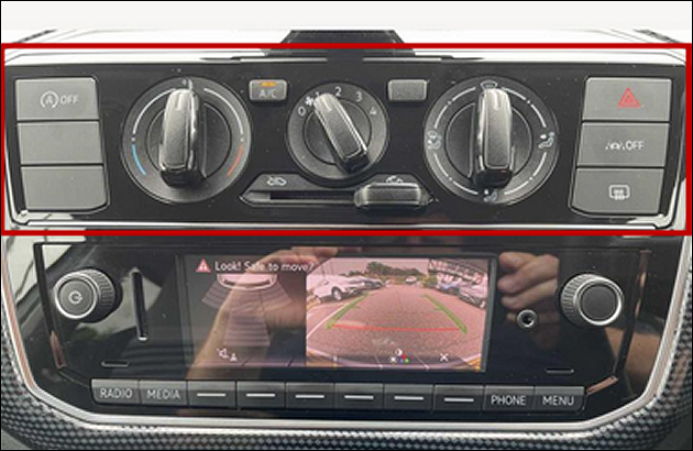 part of a 2023 Volkswagen dashboard showing large rotary ventilation controls of the type which have been common for 40 years - above a modern 4 inch TV screen connected to a reversing camera 